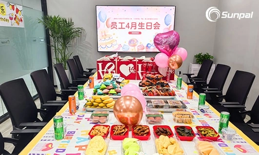 Office meeting room decorated with balloons, snacks, and drinks for April birthday party.