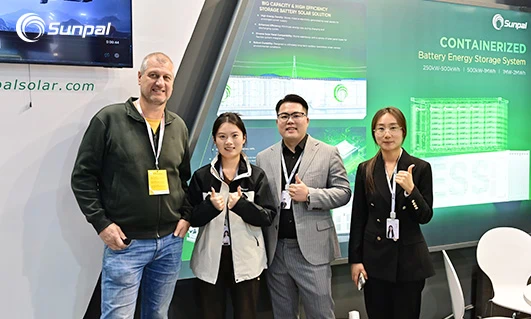 A mixed group of professionals at a Sunpal booth, posing in front of green solar displays.